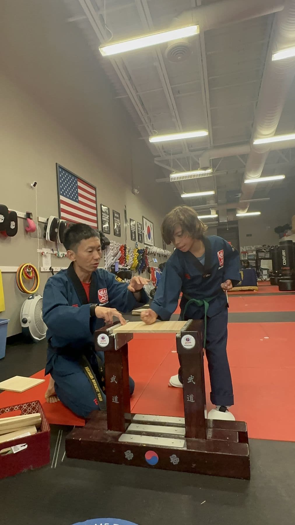 A student lines up a strike at the board-breaking stand while Master Jay holds it