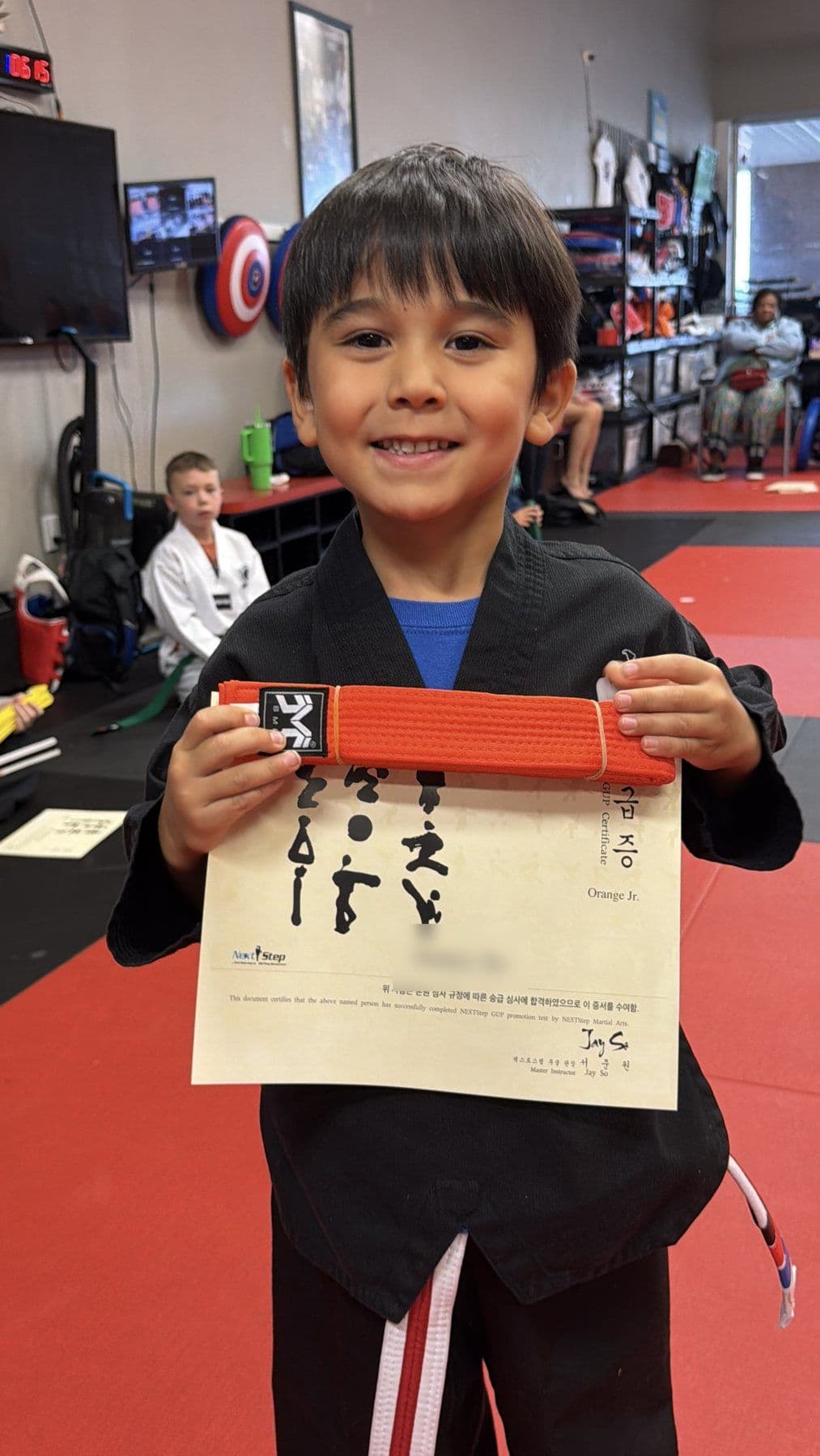 A Tiny Tiger grinning with his new orange belt and certificate