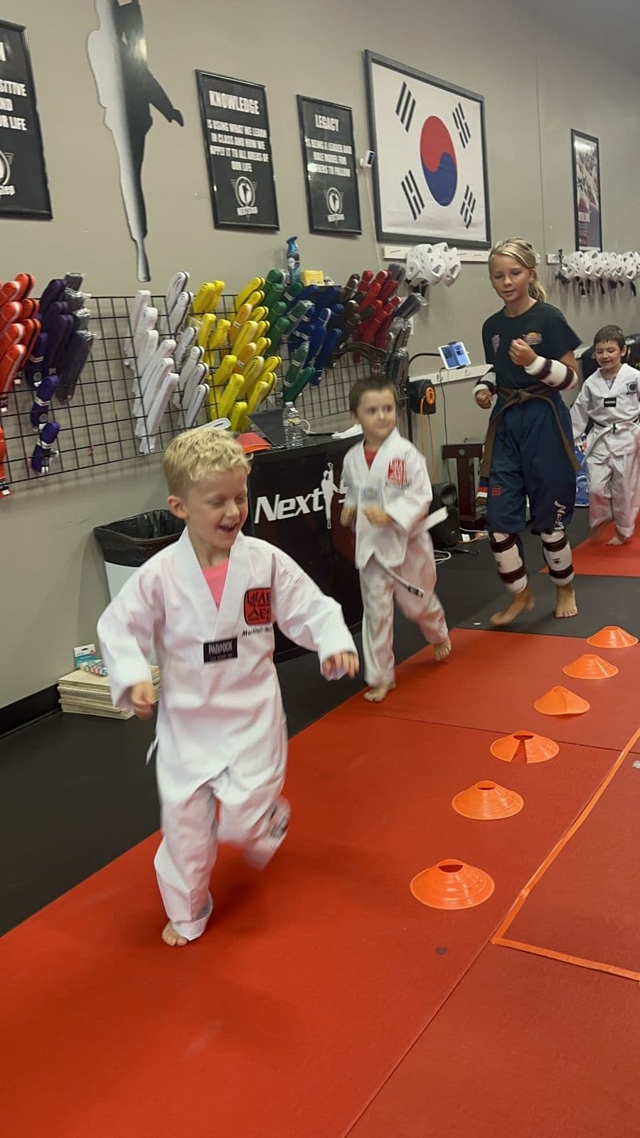 Young students running a footwork drill through cones in class