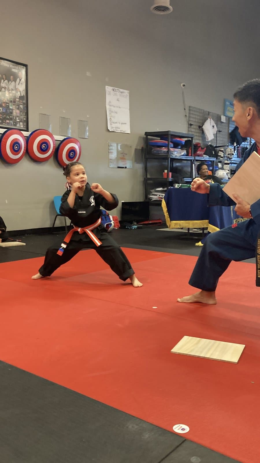 A student holds a fighting stance in front of Master Jay while families watch a belt test