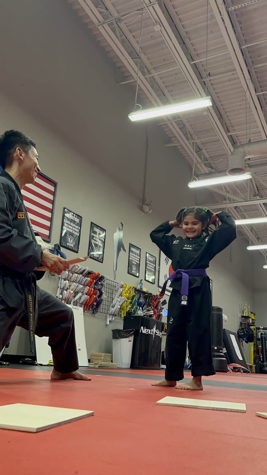 A student throws both arms up after breaking her board at a belt test